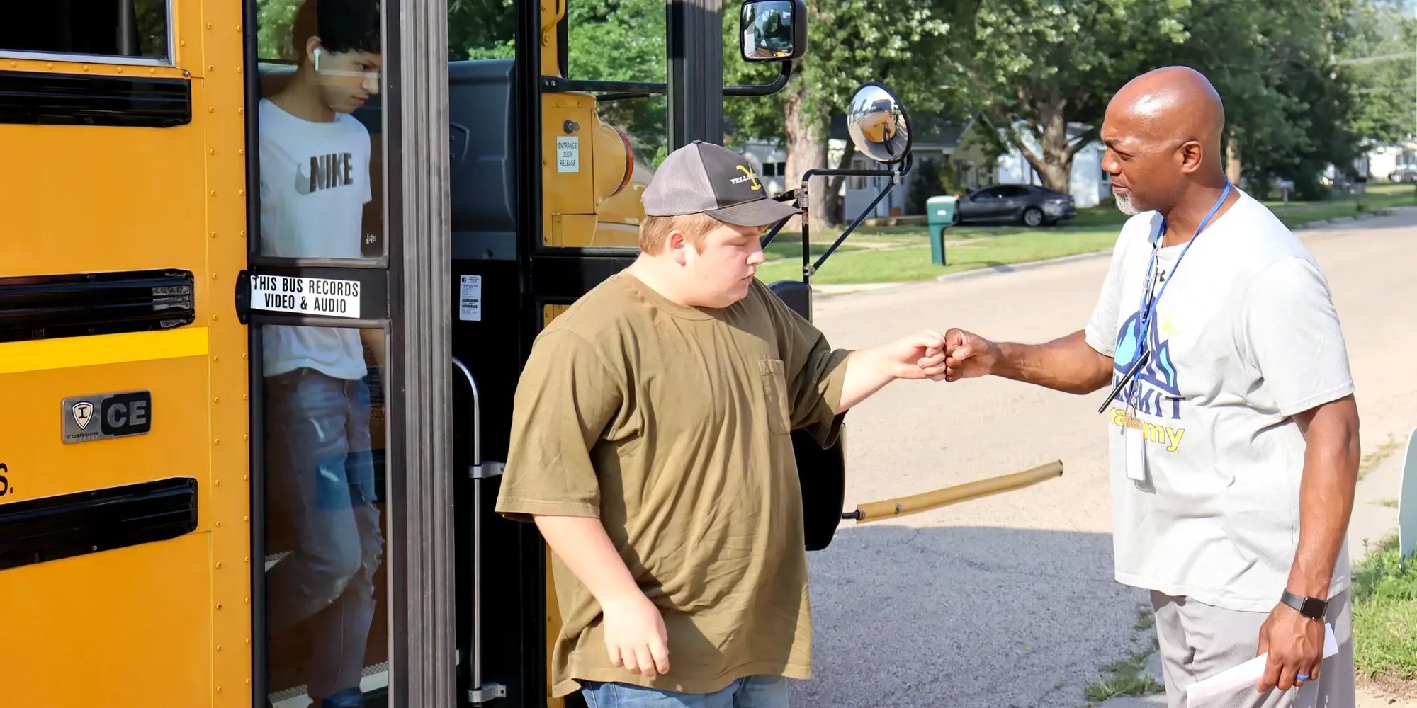 Teacher greeting student getting off the bus
